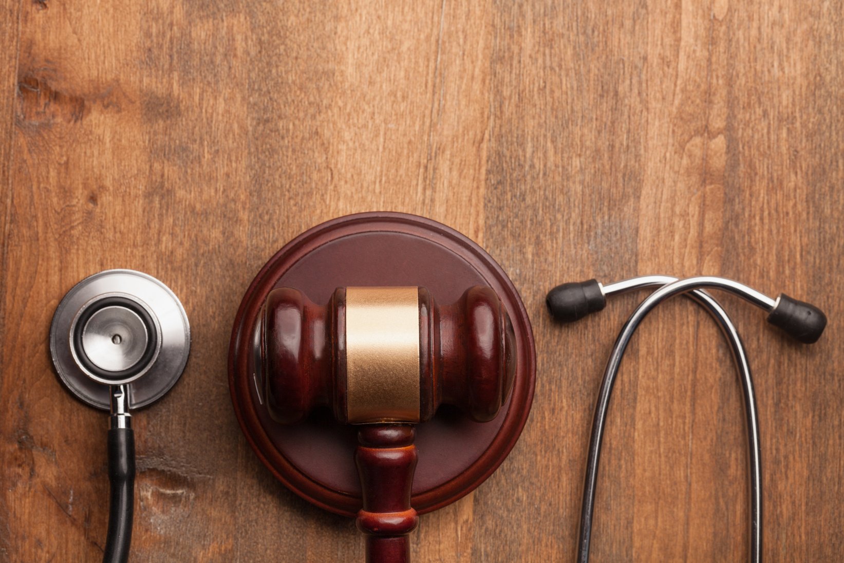 Gavel and Stethoscope on Wooden Background, Symbol Photo for Bungling and Medical Error